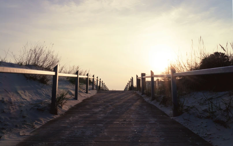 a boardwalk with wooden boards leads to the beach