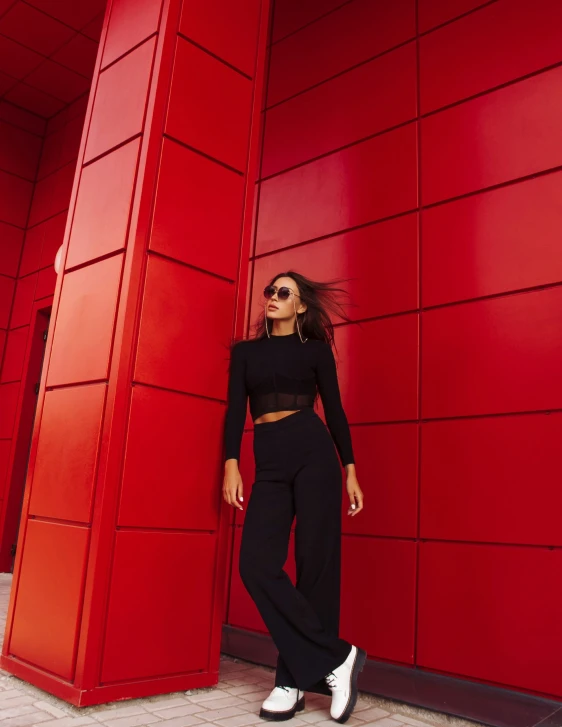 a woman poses in front of red wall with her hair down