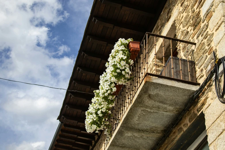 a balcony with white flowers on it is next to an old brick building