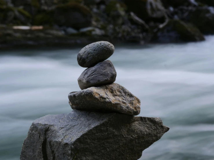 a pile of rocks sitting on top of a rock in the middle of water