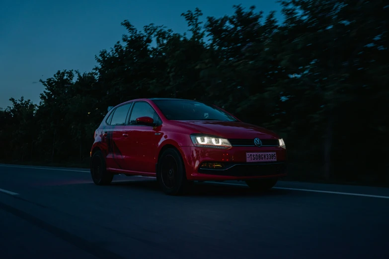 a red car drives on a dark highway