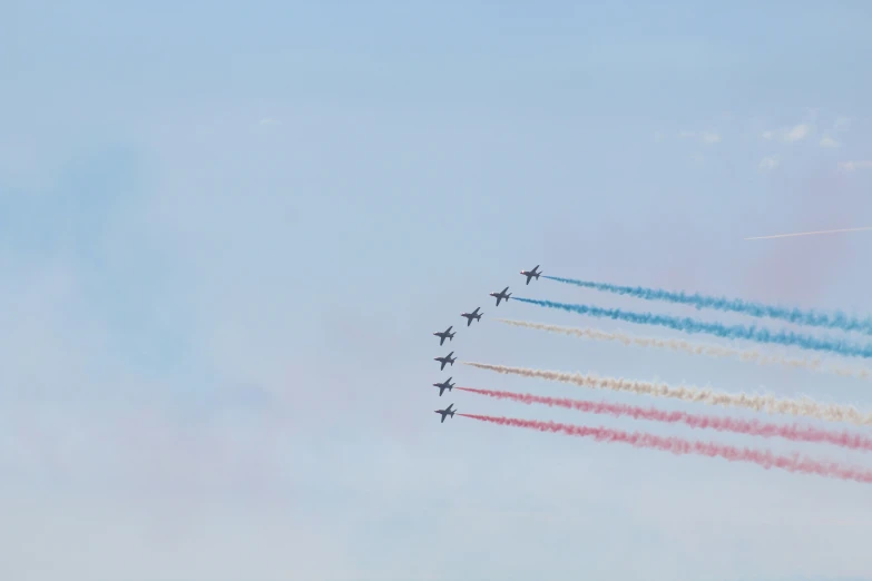 nine jets are flying together with colored smoke trails