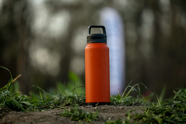 a red water bottle sits on the ground