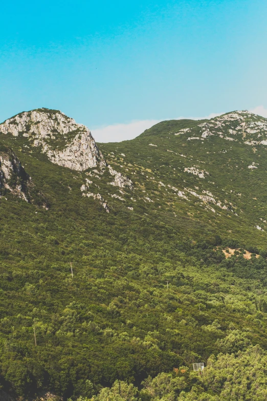 a mountain is shown with tall green mountains in the distance