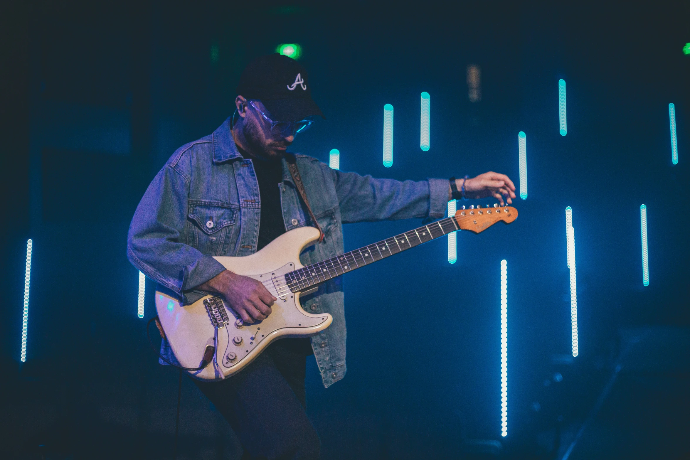 a man playing guitar in front of blue light