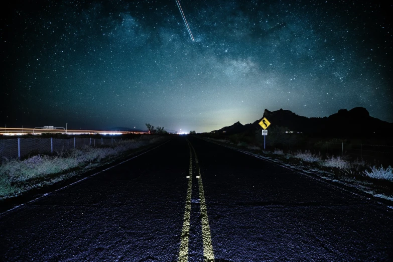 the stars shine brightly in the night sky above a deserted highway