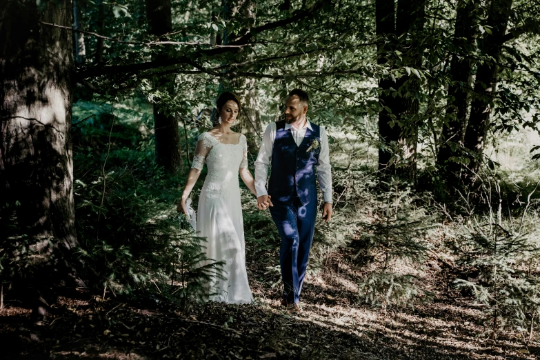 the man and woman are holding hands under the trees