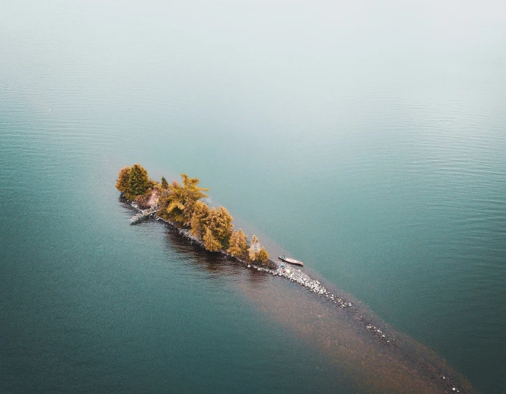 an island surrounded by trees in the middle of the ocean