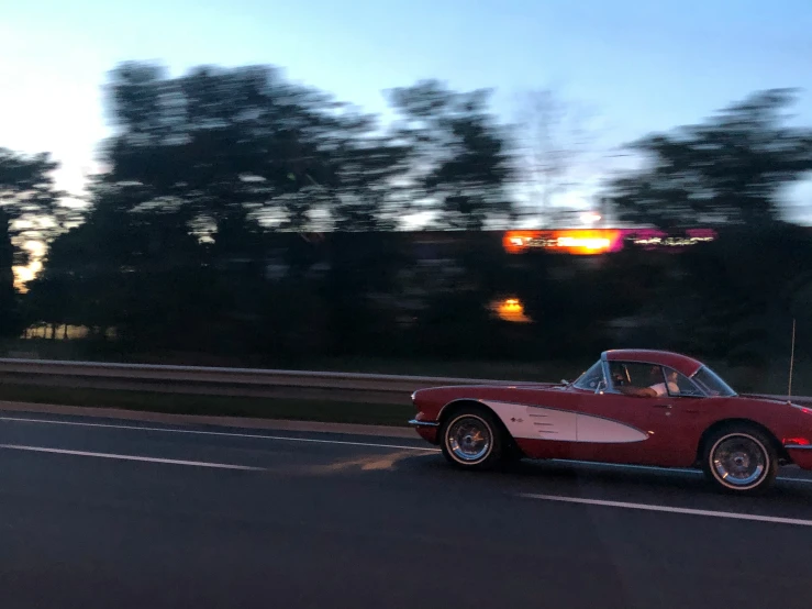 the classic sports car is driving down the road