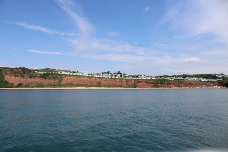 the ocean is blue and green with a hillside in the background