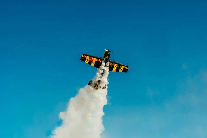 a biplane flying in the sky with the smoke coming out from its belly