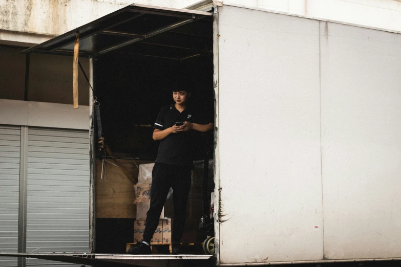 a man on his phone stands outside of a truck