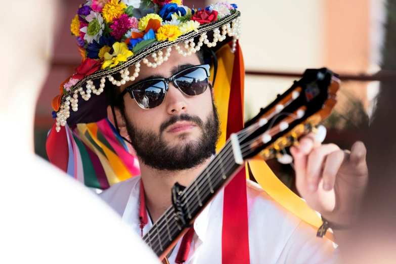 a man in sunglasses and colorful hat playing guitar