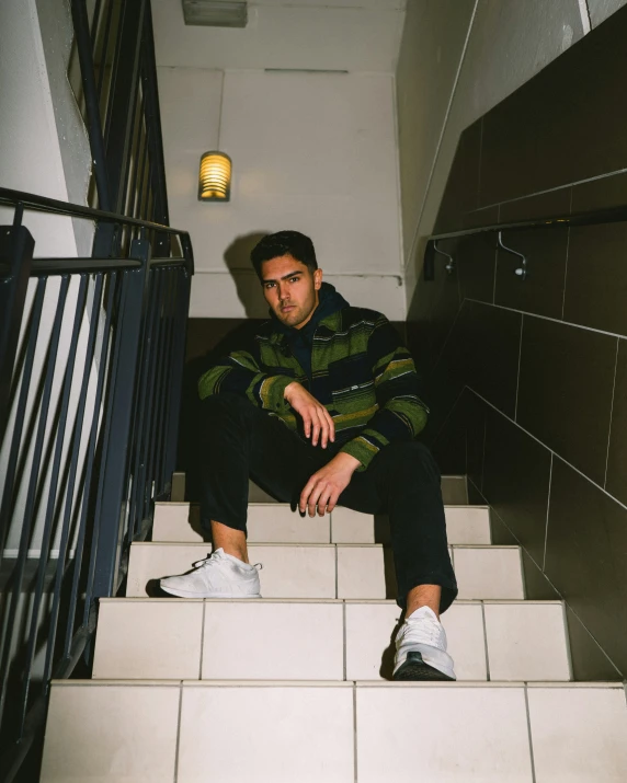 a man sitting on a flight of stairs wearing sneakers