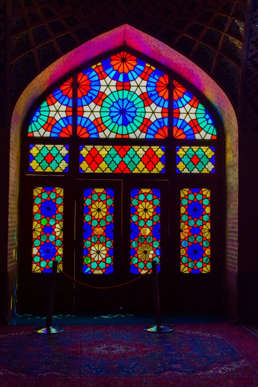 an arched stained glass door with a bench in front