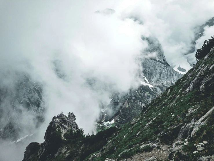 many clouds float over the tops of a mountain