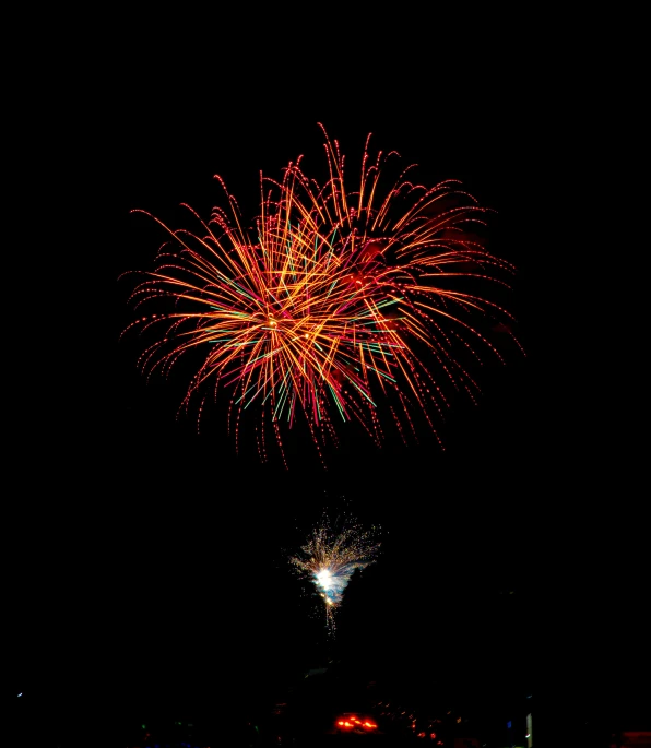 red fireworks on dark night sky with water reflection