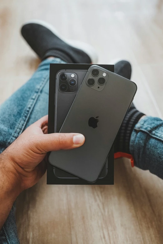 someone sitting on the ground holding two iphones