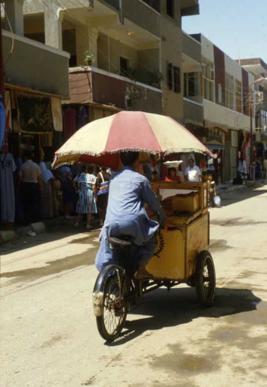 a man riding a bike and small cart