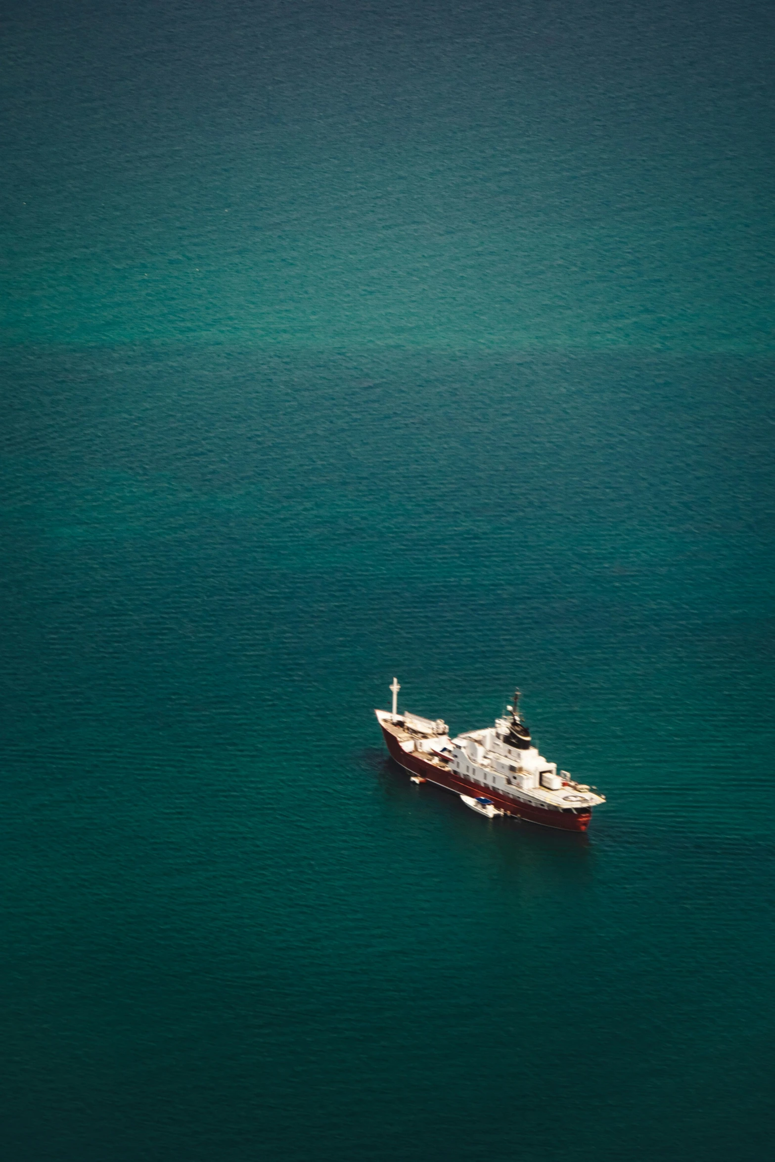 a boat with two smaller ones floating near the shoreline