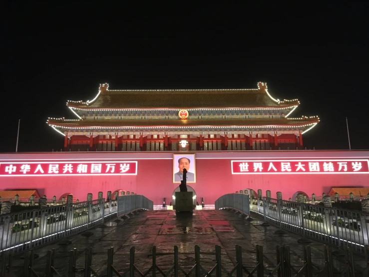 an asian building with red lights above it and a man standing on top of the stairs