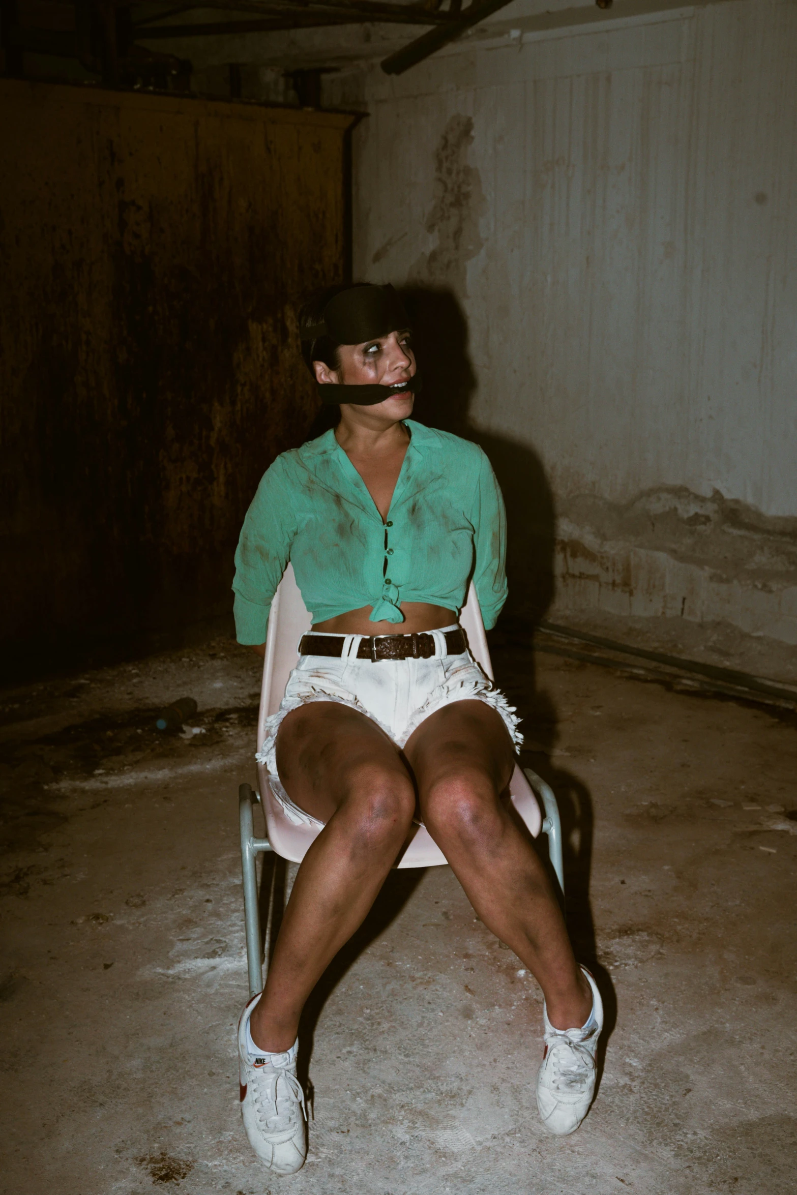 a man with glasses sitting on a folding chair in a building