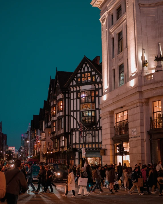 a street scene with people walking and people cross the street at night