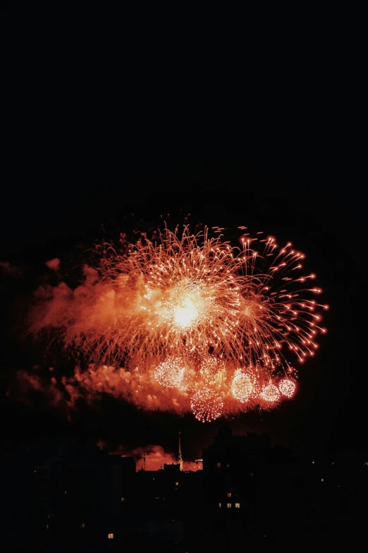 fireworks in the sky with dark skies and buildings in background