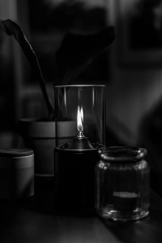 a lit candle in a glass on a desk