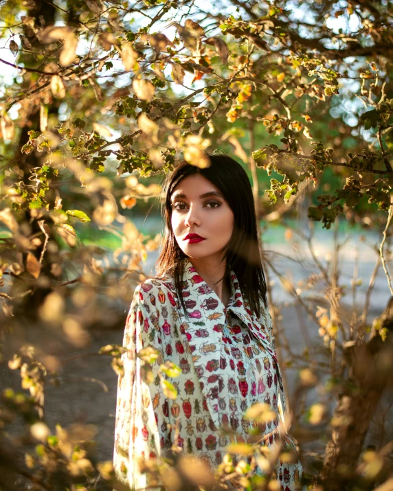 a woman standing under a tree on a sunny day