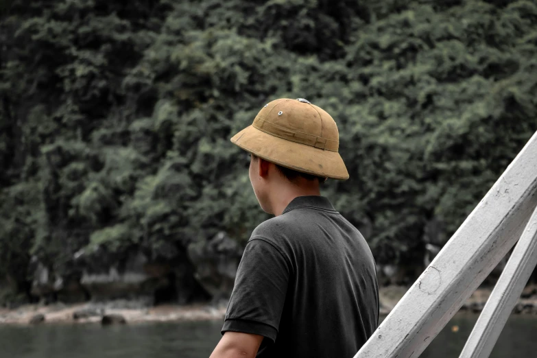 the back of a man wearing a hat looking at trees