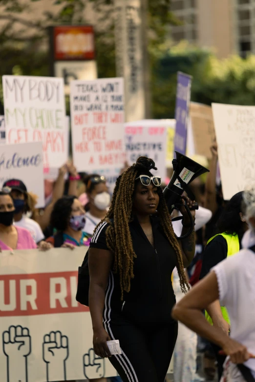 women with long dreads holding signs walking in a crowd