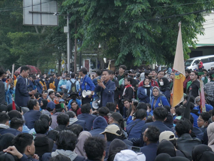 many people gathered around one man is holding an orange sign