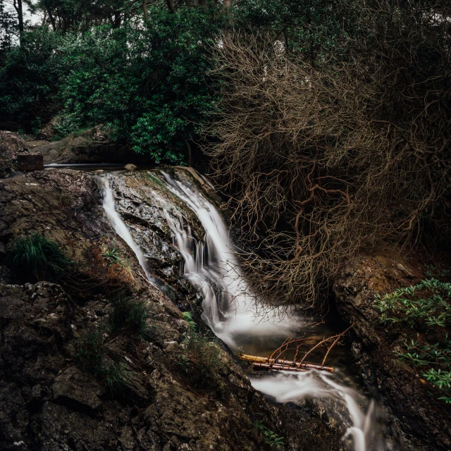 a long flowing waterfall with no water near a lush green hillside