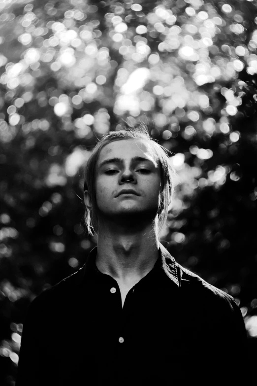 a man in black shirt standing next to a forest