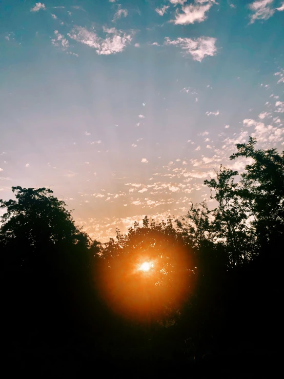 a very bright sun in the sky above some trees