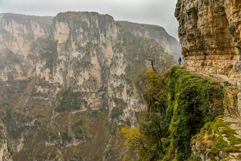 two people on a cliff overlooking the green hills