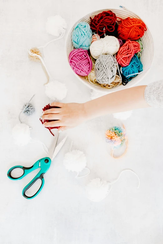 a hand on a table with crochet hooks and scissors