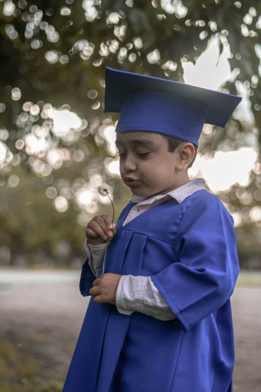 a small boy is wearing a graduation cap and gown