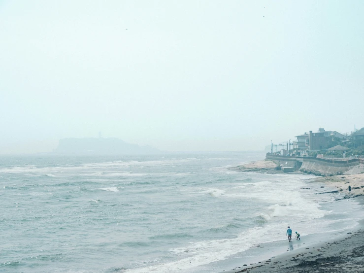 two people walking along the beach in the rain