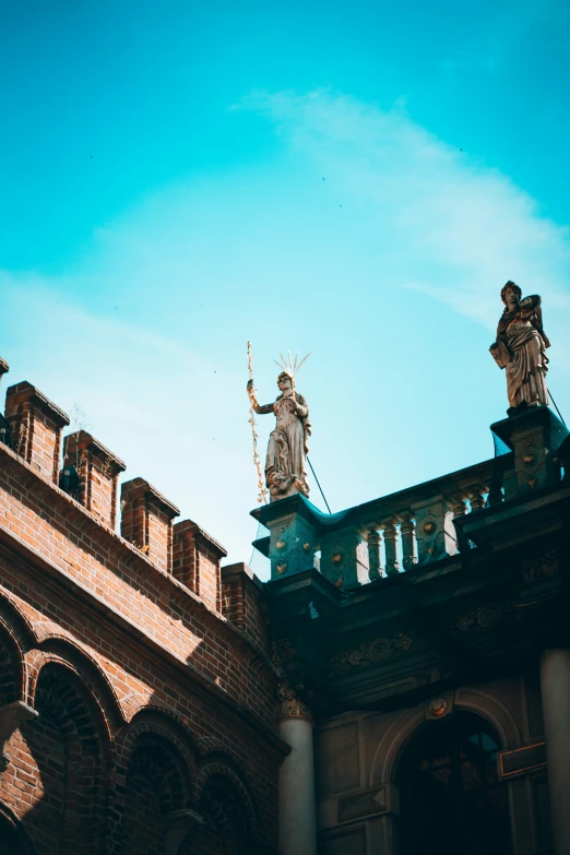 a statue holding a staff on top of a building