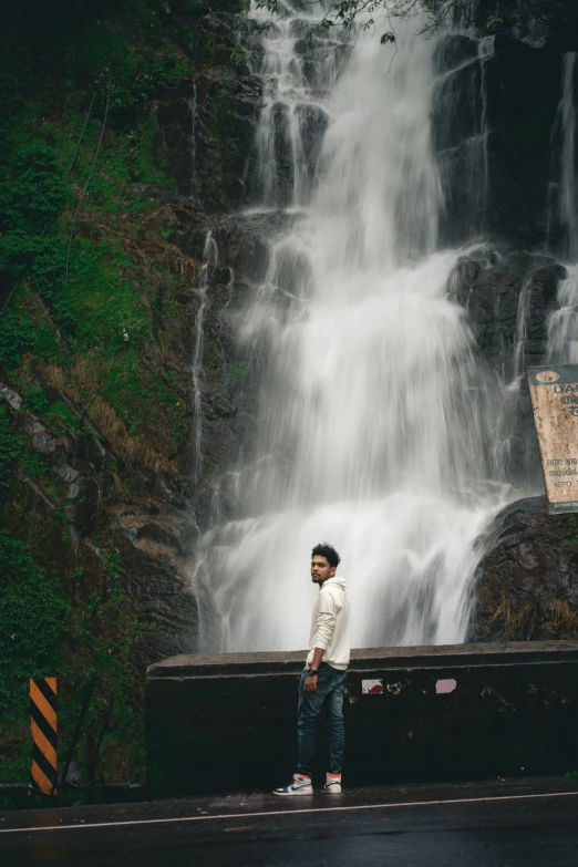 a man is standing in front of a large waterfall