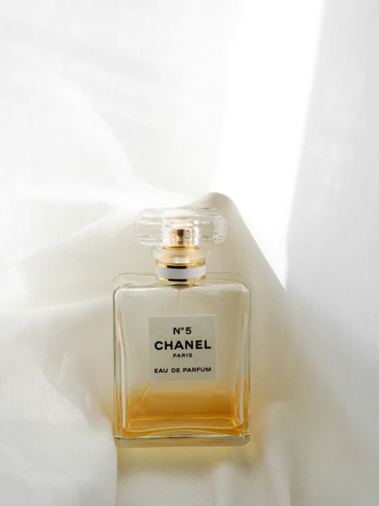 an empty bottle of perfume sitting on a bed