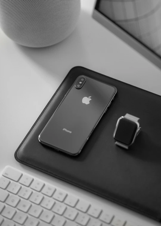 black and white pograph of an iphone on a table with keyboard