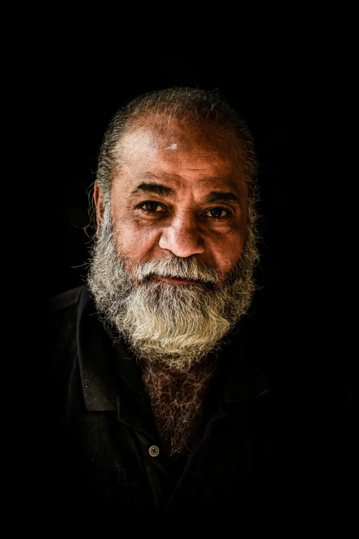 a man with grey hair and beards looks into the camera