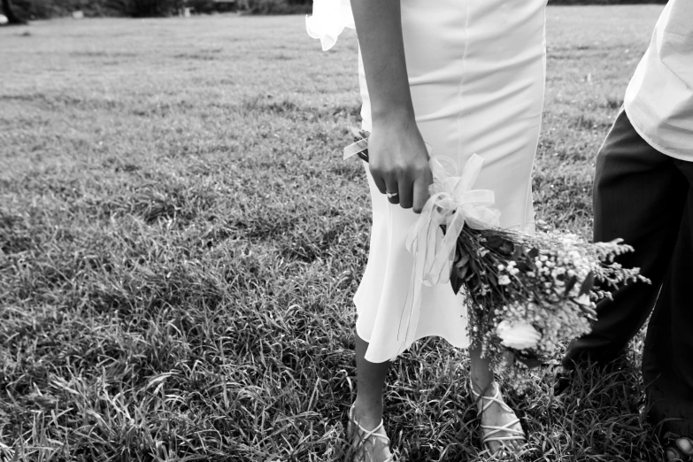 two people holding flowers in the grass with a dog