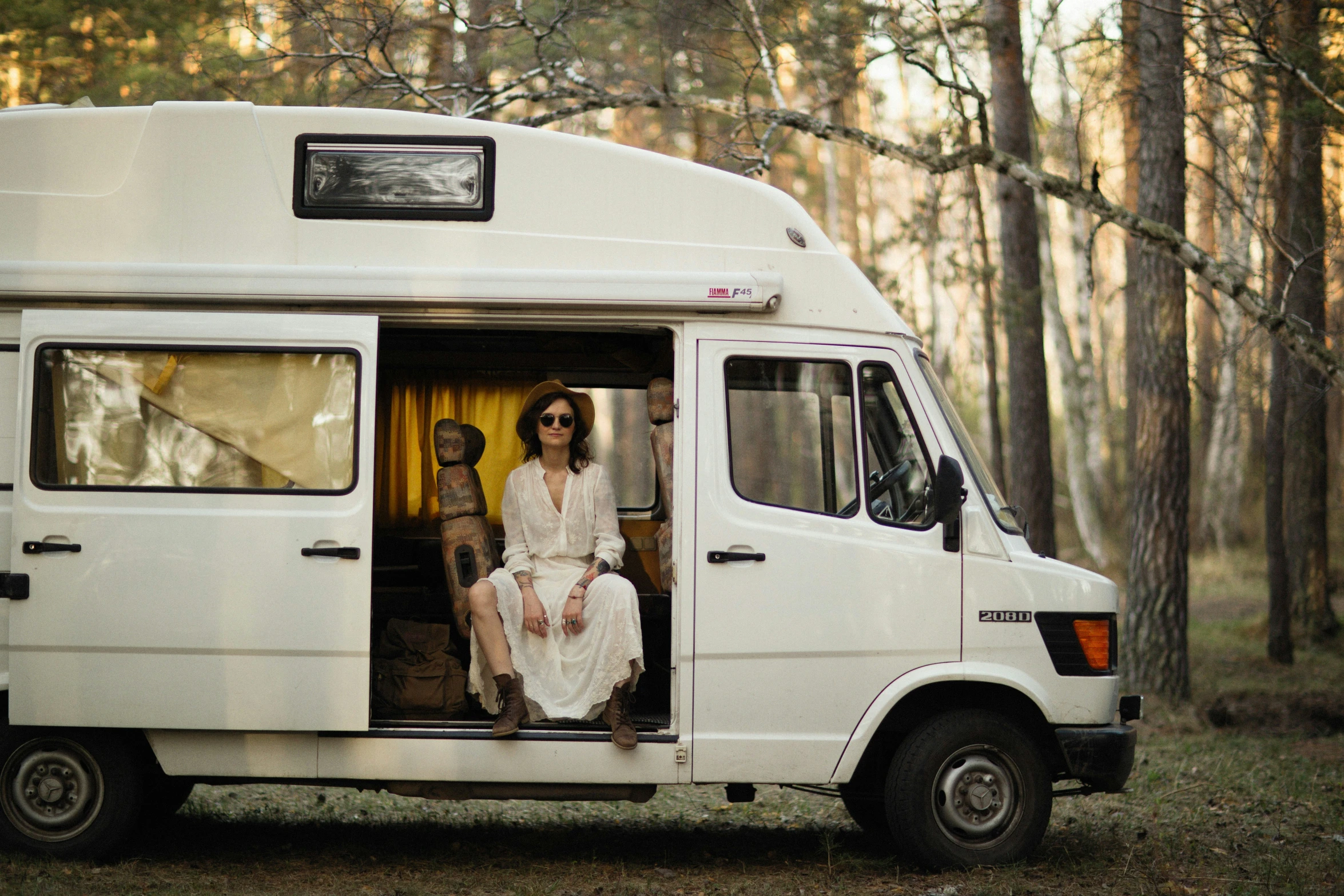 two people sitting on the open doors of a van