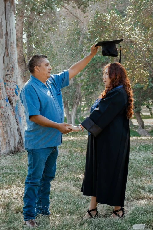 a male graduate is giving an old woman his mortar