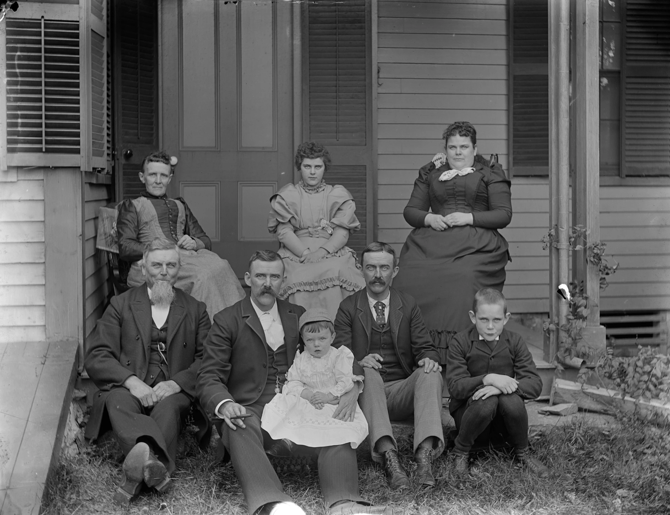 an old po of many people sitting outside of a house