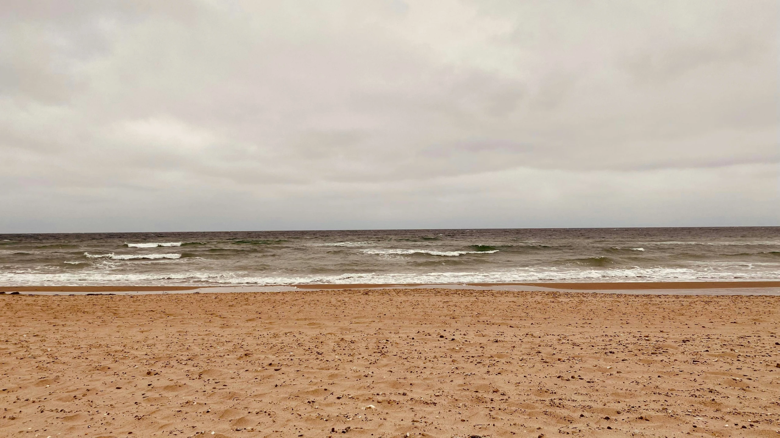 there is a bench on the beach near water